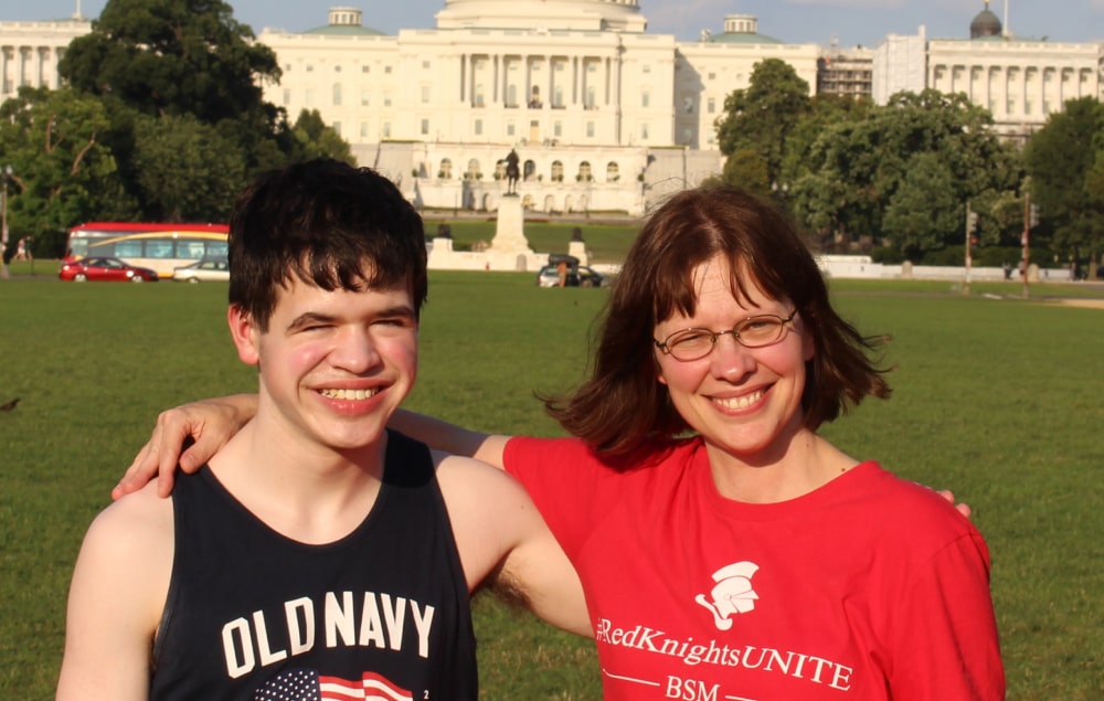 Voters for Cures champion Alisa May, caregiver to her son Justin, standing with arms over each other's shoulders in front of the U.S. Capitol building