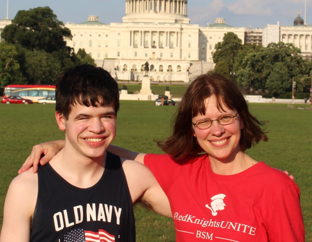 Voters for Cures champion Alisa May, caregiver to her son Justin, standing with arms over each other's shoulders in front of the U.S. Capitol building